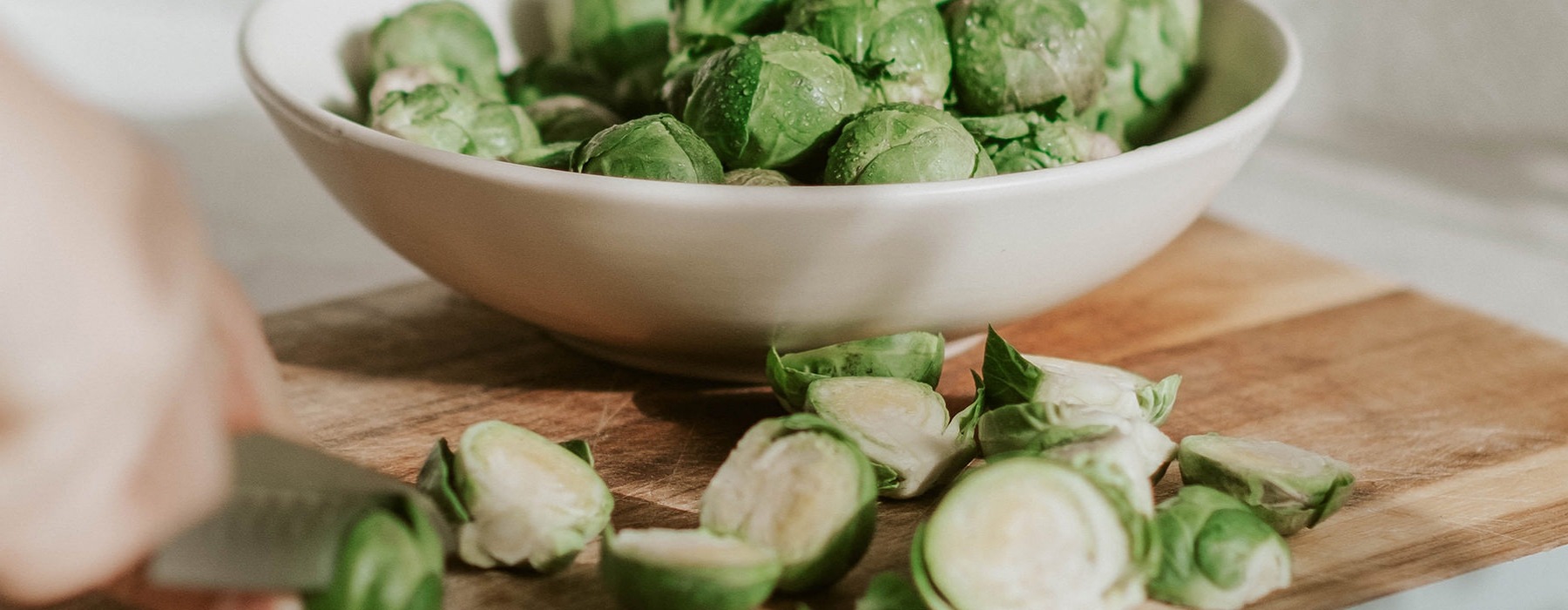 Bowl of sliced brussell sprouts sitting on a cutting board